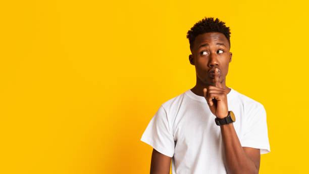 istock Amazed young african guy keeping finger on lips 1209015040