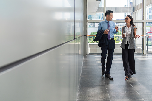 Business people  talking and walking in modern hallway with big windows