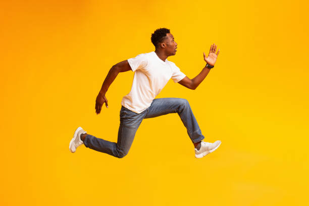 African guy jump, run fast, hurry up to sales or discounts African guy jump, run fast, hurry up to sales or discounts, wear casual style clothes sneakers on yellow color background runaway stock pictures, royalty-free photos & images