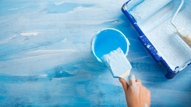 istock Hand Dips a brush in jar of blue paint 1209015937
