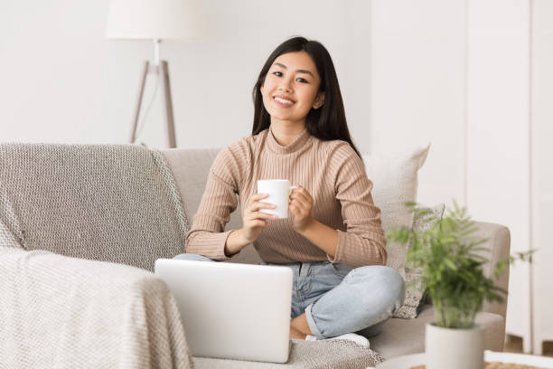 istock Enjoy weekend. Asian girl relaxing, drinking coffee and using laptop 1209016232