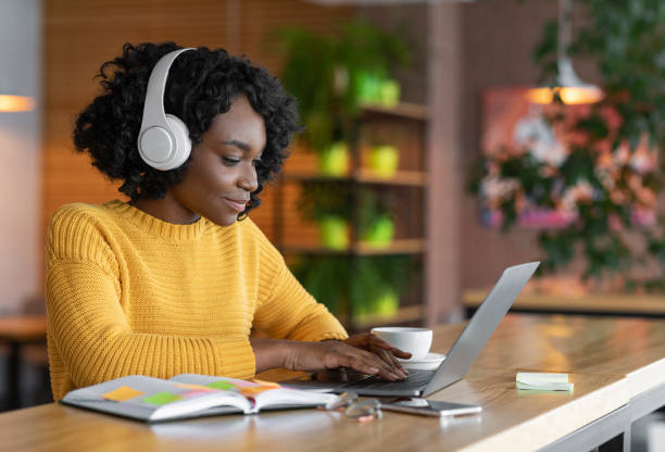 mujer joven que tiene formación en línea, utilizando portátil y auriculares inalámbricos - bluetooth headset women hands free device fotografías e imágenes de stock