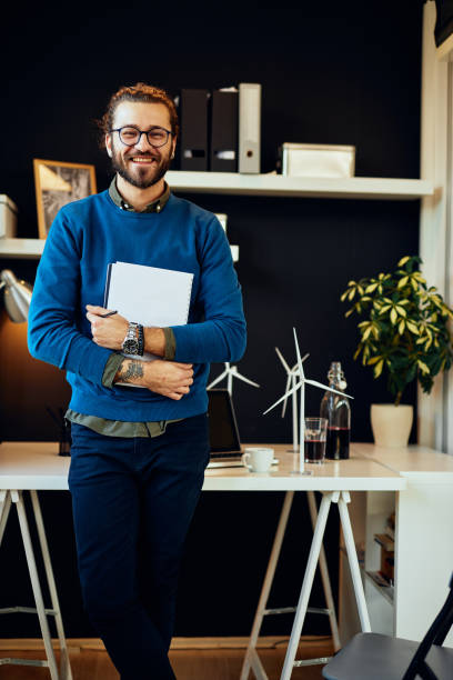 istock Handsome positive young caucasian hipster standing in his office, holding paperwork and preparing to go on meeting with important clients. 1209017782