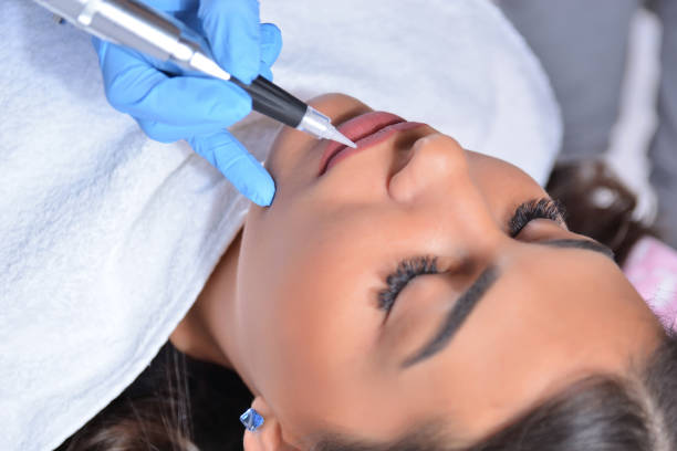 istock Young pretty girl having permanent makeup on lips in beautician salon 1209018533