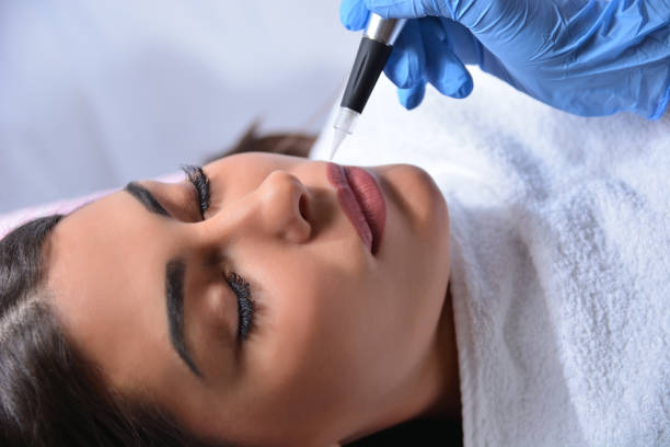 istock Cosmetologist applying permanent makeup on woman lips 1209018556
