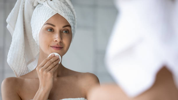 istock Head shot beautiful woman using cotton pad, looking in mirror 1209020086