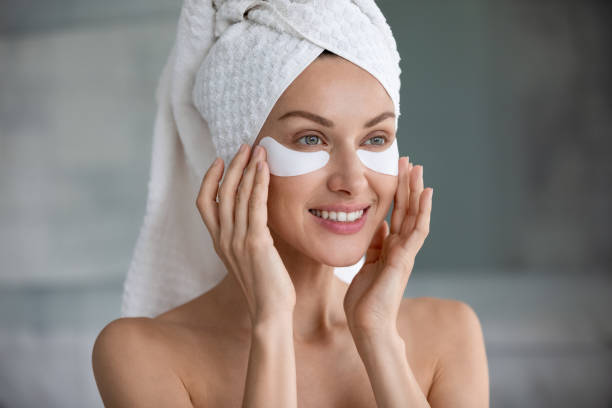 istock Head shot smiling woman applying hydrogel patches under eyes 1209020111