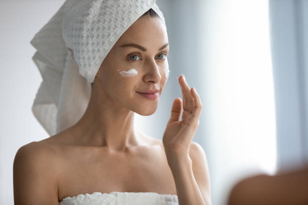 istock Close up beautiful woman applying cream, looking in mirror 1209020114