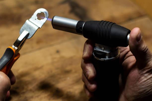 istock Old male, using torch gun in his workshop, heating up some metal equipment 1209020288