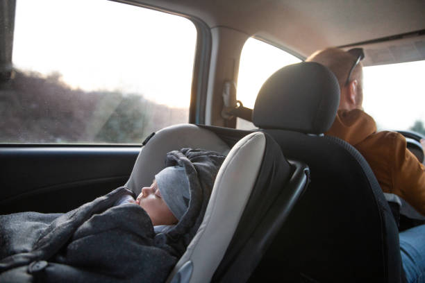 Family travel Inside of the car, baby sleeping in a car seat and father driving. baby stroller winter stock pictures, royalty-free photos & images