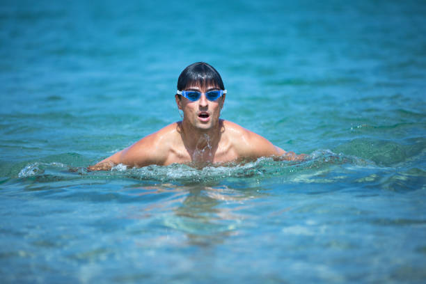 Young man swimming the front crawl in the sea (swimmer, triathlon)