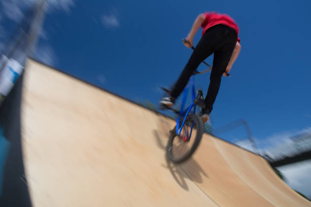 bmx всадника перепрыгивая на u рампы в скейтпарк - bmx cycling bicycle cycling backflipping стоковые фото и изображения