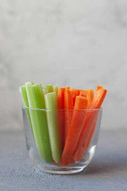 istock Diet raw sticks of celery,carrots in glass on light grey backgraund. copy space 1209029098