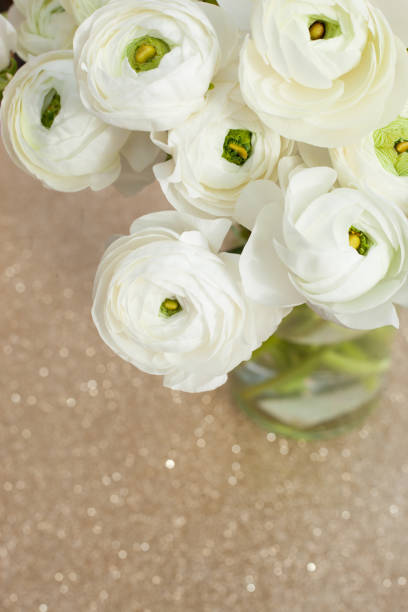 Close-up, overhead view of flowers on a beige textured background. Chrysanthemum, rannuculus, bells of Ireland.