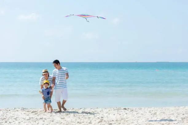 Happy family summer sea  beach vacation. Asia young people lifestyle travel play kite enjoy fun and relax in holiday. Travel and Family Concept