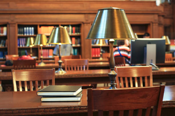 Pretty college girl studying in the library. Taking notes and using headphones, tablet and phone.