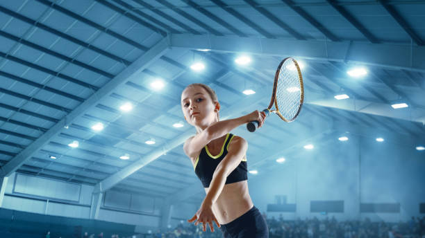 piccola ragazza caucasica che gioca a tennis sullo sfondo del campo sportivo - tennis child teenager childhood foto e immagini stock