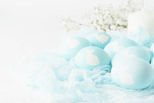 istock Easter. Holiday. Light white background, gentle pastel colors. Blue eggs with image of rabbit 1209033066