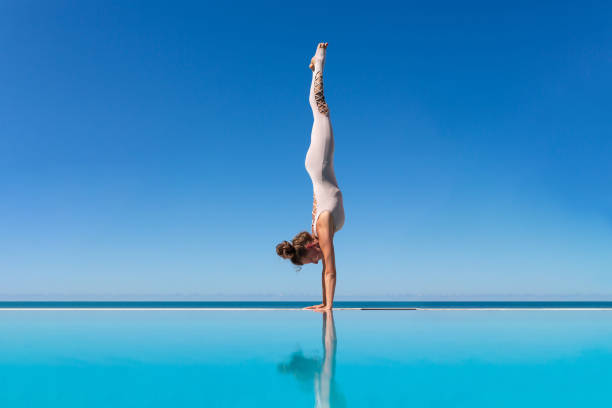 istock woman doing yoga on poolside. 1209036200