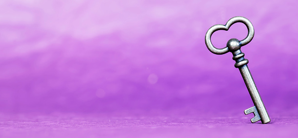 Escape room concept. Vintage key on purple background, web banner with text copy space.