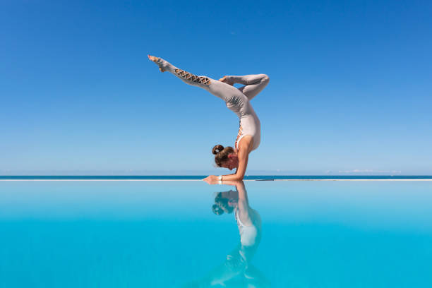 istock woman doing yoga on poolside. 1209036799