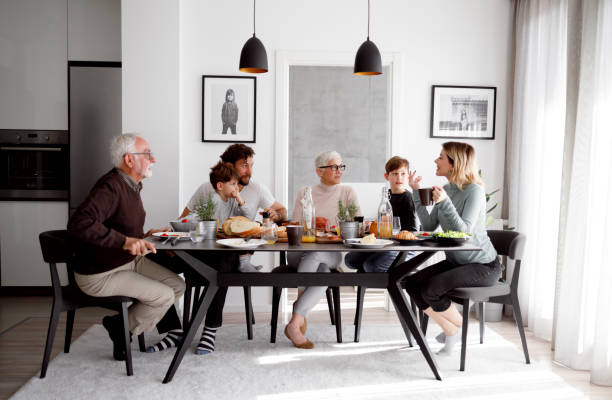 Lunch time Multi generational family is having a breakfast at the table in the bright apartment. dining table stock pictures, royalty-free photos & images