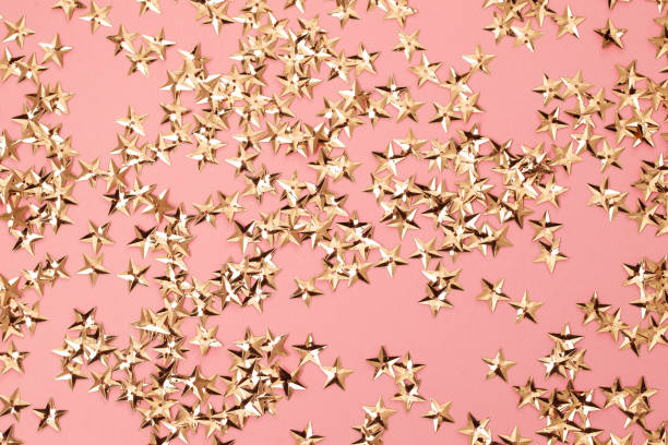 istock small golden stars on pink background 1209040957