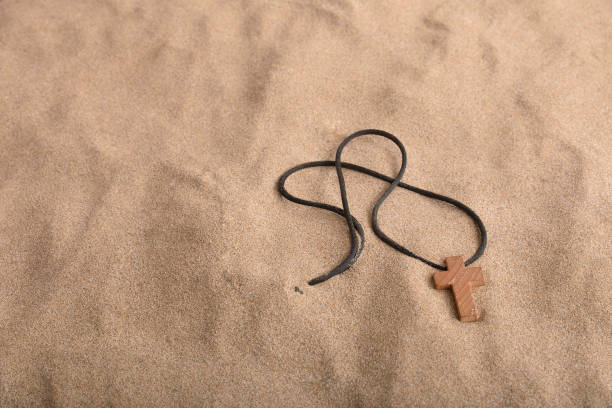 istock Wooden crucifix half buried in sand with black cord 1209045213