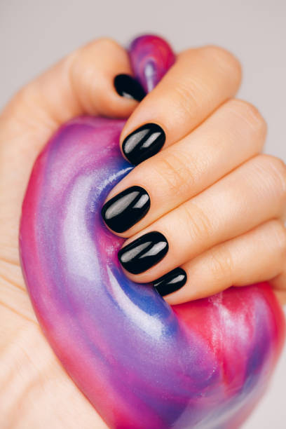 istock hands with black manicure holding slime 1209047492