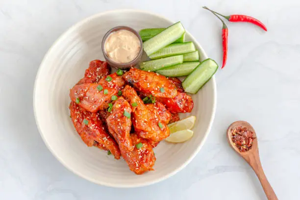 Spicy Baked Chicken Wings Served with Mayonnaise Dip, Cucumber, Lemon, Red Chili, and Sesame Seeds,  Directly Above Horizontal Stock Photo
