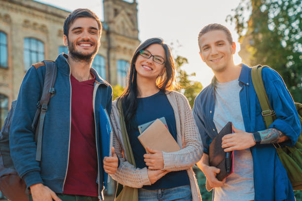 Group of diverse students outside smiling together near university stock photo