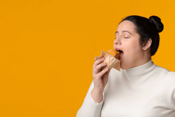 istock Hungry Plus Size Girl Eating Burger With Closed Eyes 1209051895