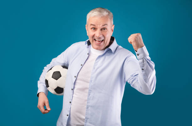 istock Man posing with soccer ball on blue background 1209053584
