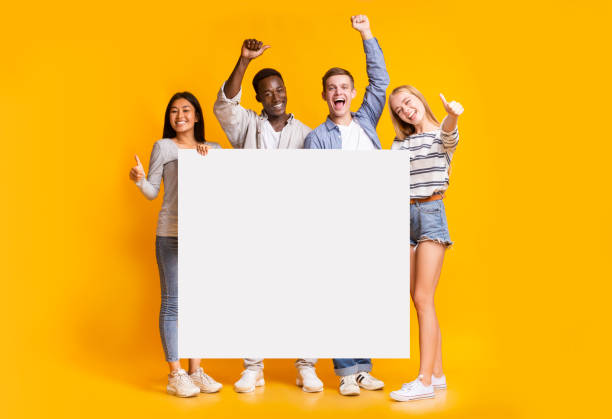 positive gruppe von teenagern, die zusammen mit weißem plakat stehen - man holding a sign stock-fotos und bilder