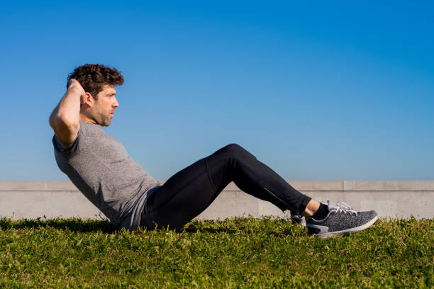 istock sportsman trains abs on the grass 1209054847