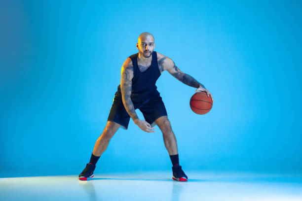istock Young basketball player training isolated on blue studio background in neon light 1209055012