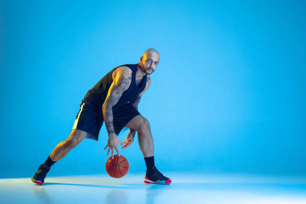 istock Young basketball player training isolated on blue studio background in neon light 1209055016