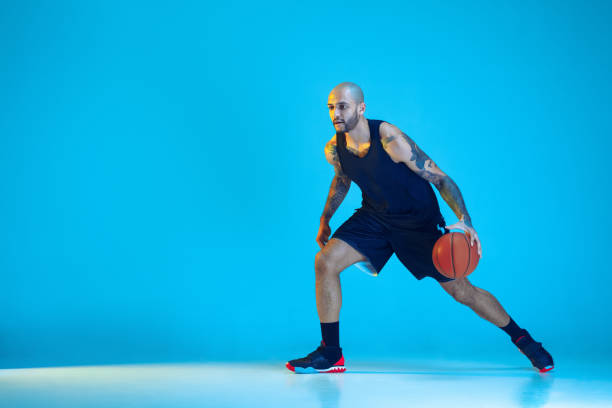 istock Young basketball player training isolated on blue studio background in neon light 1209055032