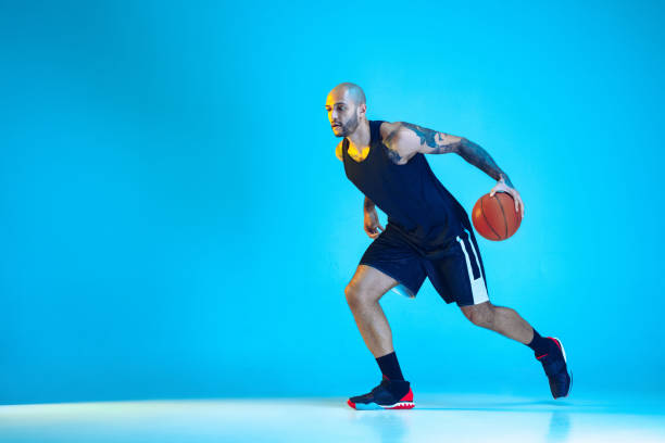 istock Young basketball player training isolated on blue studio background in neon light 1209055052