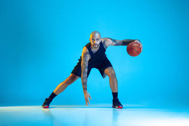 istock Young basketball player training isolated on blue studio background in neon light 1209055060