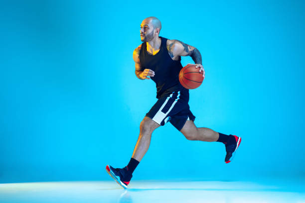 istock Young basketball player training isolated on blue studio background in neon light 1209055063