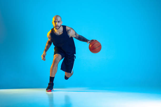 istock Young basketball player training isolated on blue studio background in neon light 1209055076