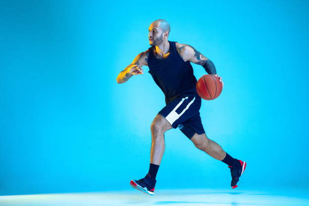 istock Young basketball player training isolated on blue studio background in neon light 1209055079