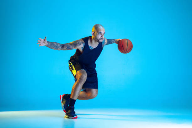 istock Young basketball player training isolated on blue studio background in neon light 1209055095