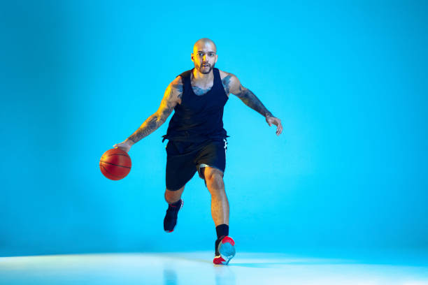 istock Young basketball player training isolated on blue studio background in neon light 1209055098