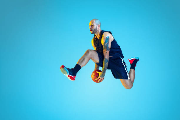 istock Young basketball player training isolated on blue studio background in neon light 1209055102