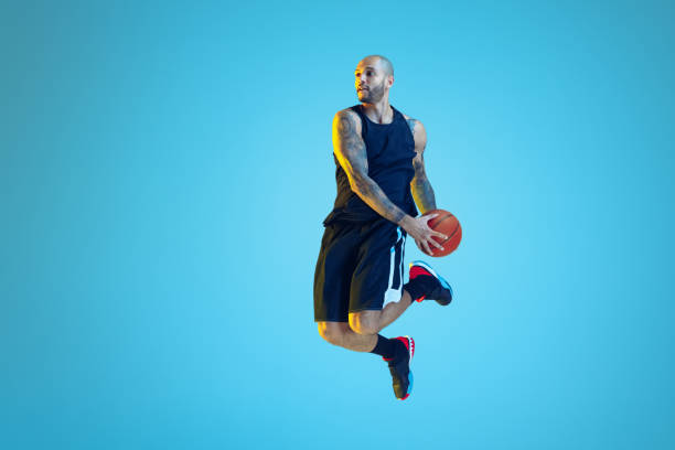 istock Young basketball player training isolated on blue studio background in neon light 1209055106