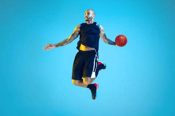 istock Young basketball player training isolated on blue studio background in neon light 1209055107