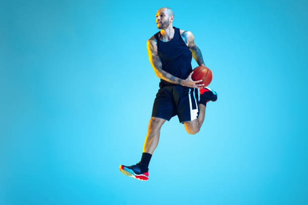 istock Young basketball player training isolated on blue studio background in neon light 1209055126