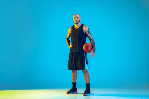 istock Young basketball player training isolated on blue studio background in neon light 1209055156